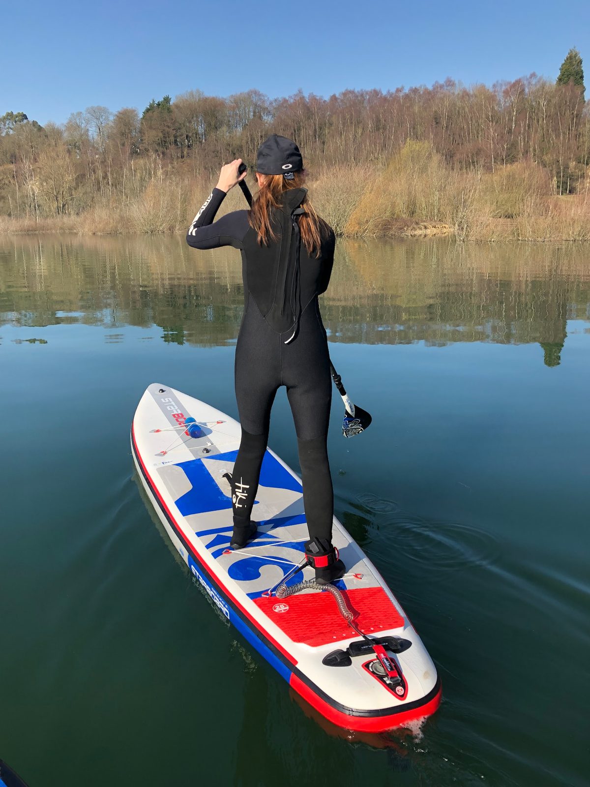 Paddler on a touring stand-up paddleboard on open water in flat winter light
