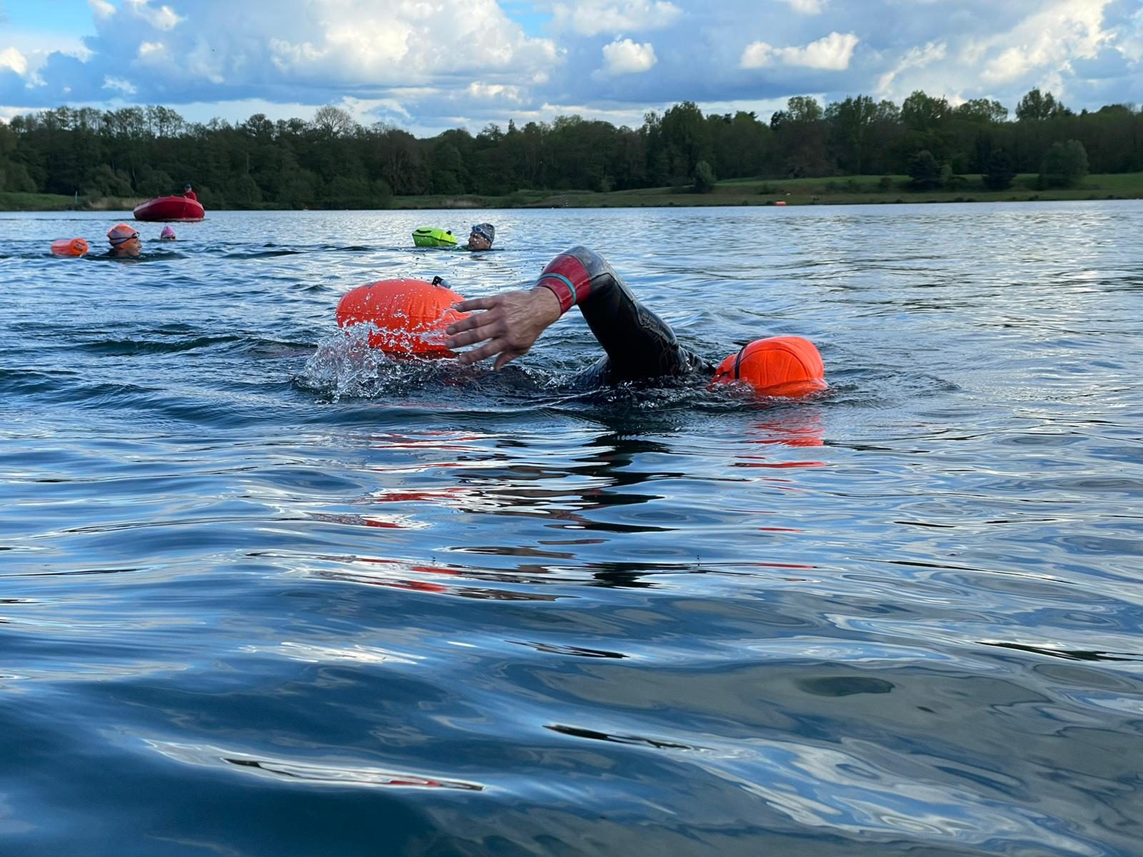 Swimmer mid front-crawl stroke in open water during a coached swim