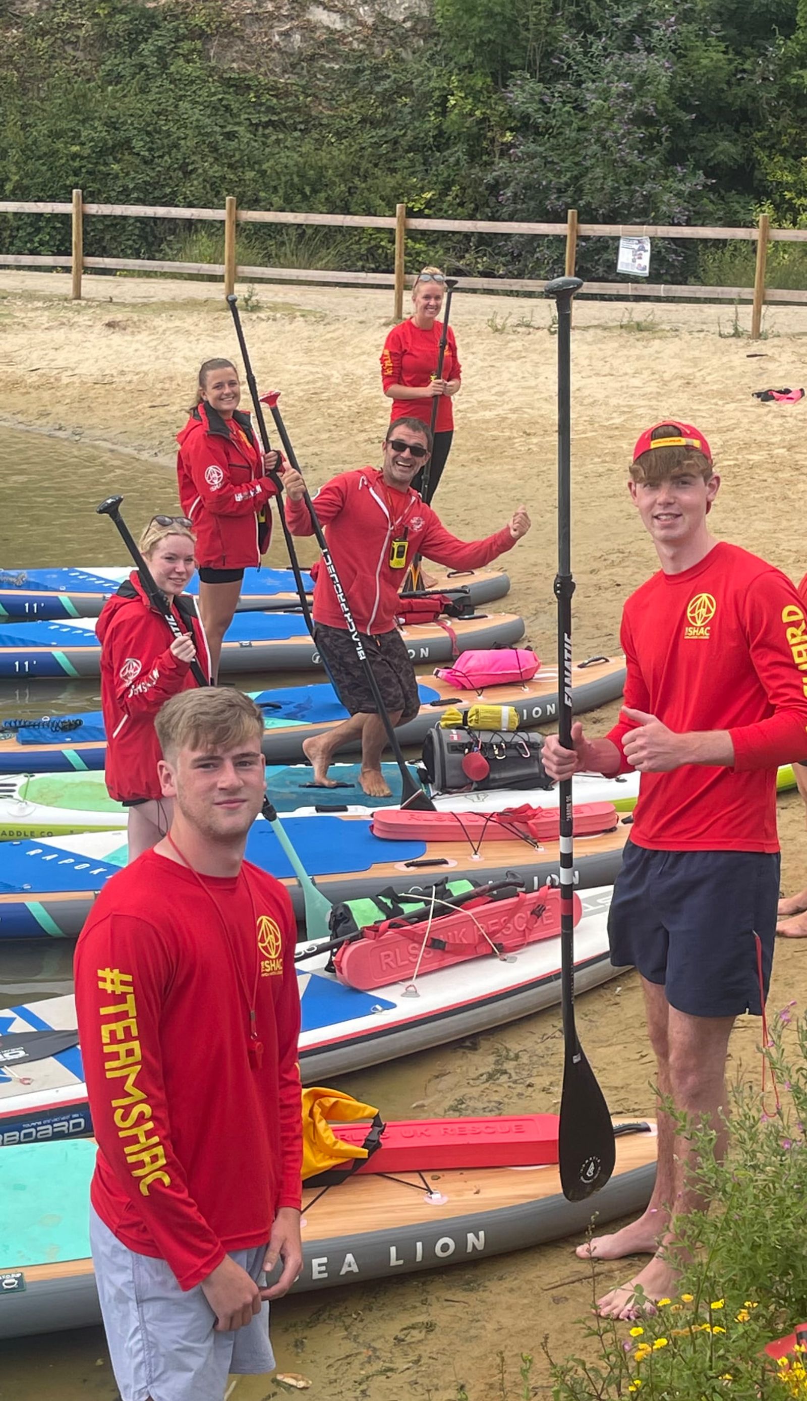 Lifeguard team on a lake shore with paddleboards, rescue tubes and radios during site-specific lifeguard training