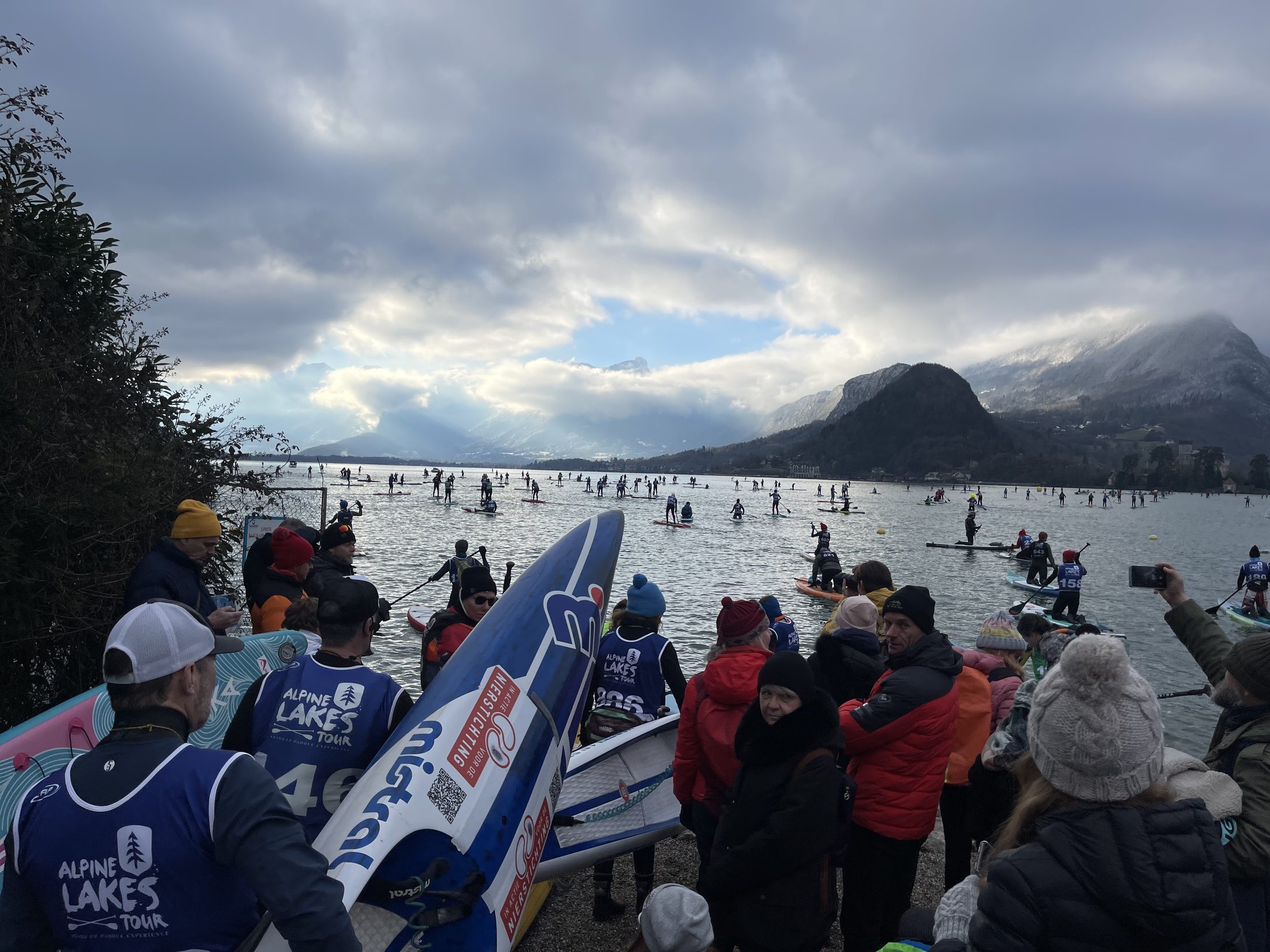 A large crowd on the shore watching hundreds of paddlers on Lake Annecy at the French Gla Gla Race