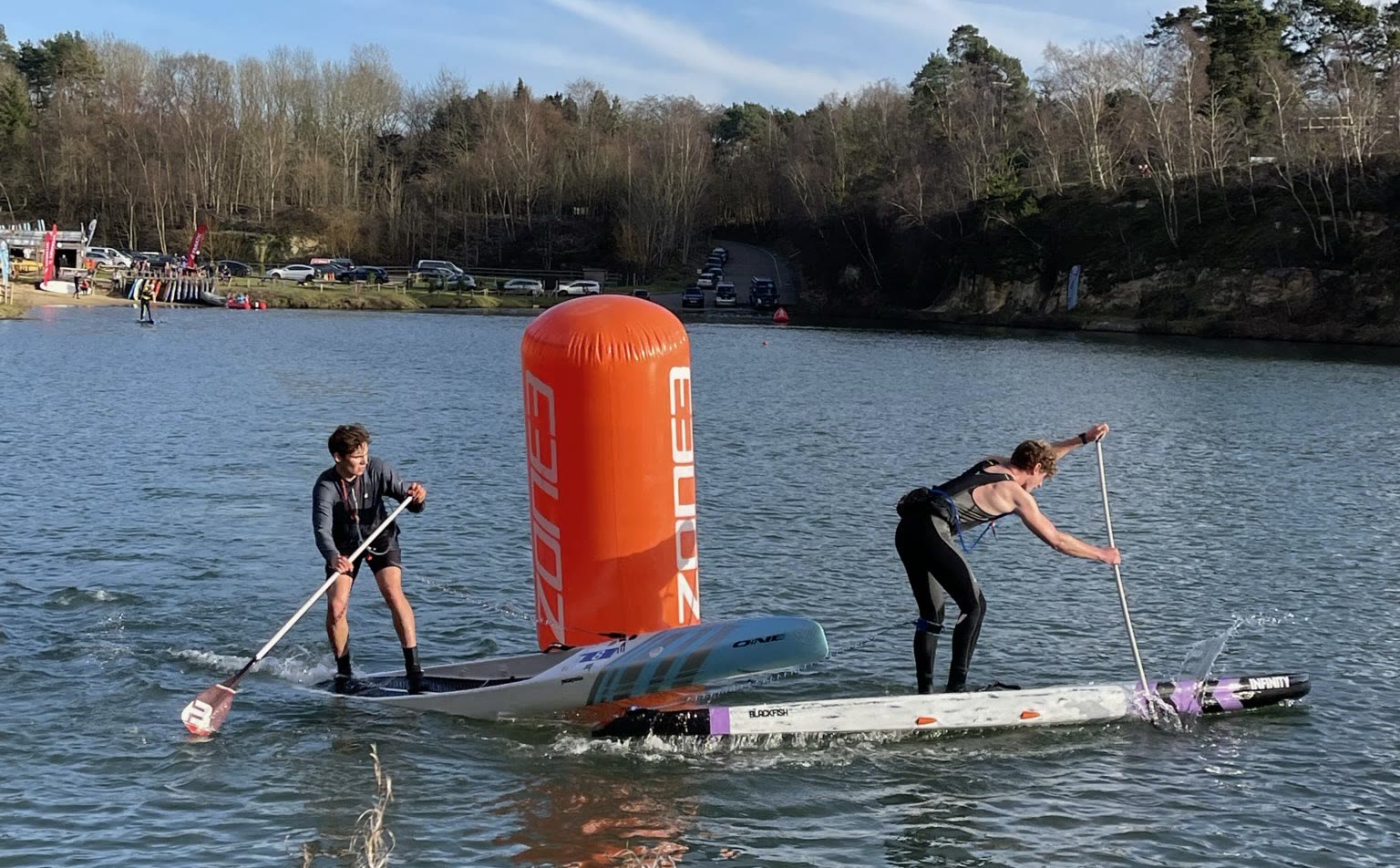 Two racers rounding an orange marker buoy side by side on the winter lake course at GLAGLA UK